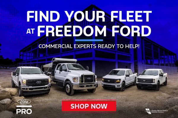 Lineup of Ford commercial trucks and work vehicles parked in front of a steel-frame construction site, with the text “Find Your Fleet at Freedom Ford – Commercial Experts Ready to Help!”